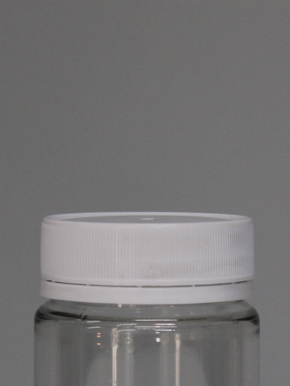 A clear, round, smooth-sided PET Cosmetic jar with a white tamper lid.