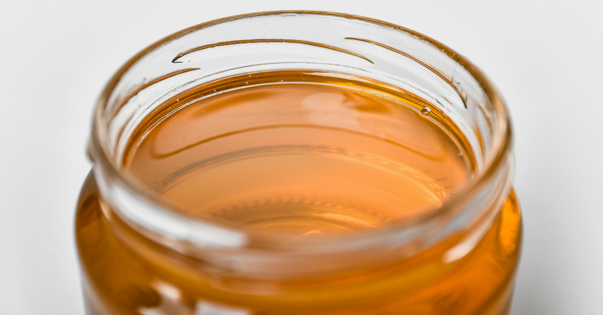 Close-up of an open honey jar filled with golden honey